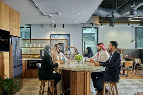 Professionals gather over coffee in a stylish Servcorp coworking kitchen in Saudi Arabia, fostering connection and collaboration.