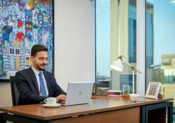 A professional works confidently from a private Servcorp office in Saudi Arabia, enjoying premium workspace design with skyline views and cultural flair.
